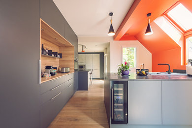 Cette image montre une grande cuisine ouverte linéaire minimaliste avec un placard à porte affleurante, des portes de placard grises et un plan de travail en stratifié.