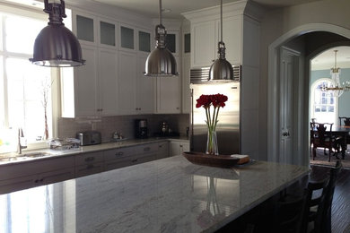 Example of a large trendy u-shaped medium tone wood floor eat-in kitchen design in Other with recessed-panel cabinets, white cabinets, granite countertops, beige backsplash, subway tile backsplash, stainless steel appliances and an island
