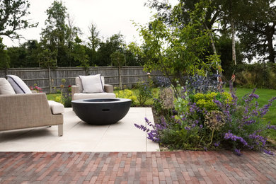 Inspiration for a medium sized modern back patio in Sussex with a fireplace, natural stone paving and a pergola.