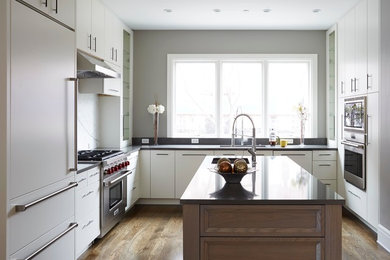 Mid-sized trendy u-shaped medium tone wood floor eat-in kitchen photo in Chicago with an undermount sink, flat-panel cabinets, white cabinets, granite countertops, white backsplash, stone slab backsplash, stainless steel appliances and an island