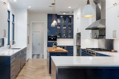 Eat-in kitchen - mid-sized contemporary u-shaped light wood floor and beige floor eat-in kitchen idea in Austin with an undermount sink, flat-panel cabinets, blue cabinets, quartz countertops, white backsplash, ceramic backsplash, stainless steel appliances, an island and white countertops