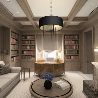 Exempel på ett stort klassiskt arbetsrum, med ett bibliotek, en spiselkrans i sten och ett fristående skrivbord