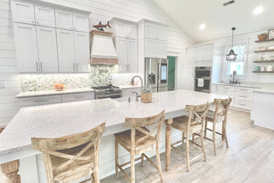 Huge beach style vinyl floor, multicolored floor and vaulted ceiling eat-in kitchen photo in Other with a farmhouse sink, shaker cabinets, white cabinets, quartzite countertops, green backsplash, ceramic backsplash, stainless steel appliances, an island and yellow countertops