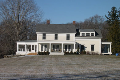 Large elegant yellow two-story exterior home photo in New York with a shingle roof