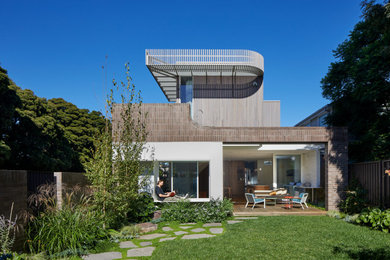 This is an example of a large contemporary two-storey brick brown house exterior in Melbourne with a flat roof, a metal roof and a grey roof.