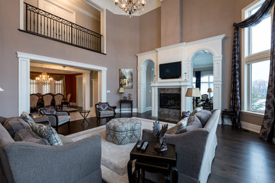 Example of a huge classic open concept dark wood floor and brown floor family room design in Toronto with beige walls, a standard fireplace, a tile fireplace and a wall-mounted tv
