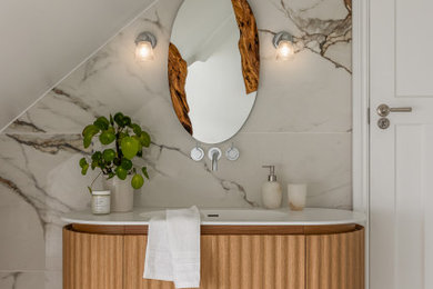 This is an example of an expansive contemporary bathroom in London with grey tiles, marble tiles, grey walls, marble flooring, marble worktops, grey floors, a single sink, a freestanding vanity unit, flat-panel cabinets, medium wood cabinets, an integrated sink, white worktops and a vaulted ceiling.