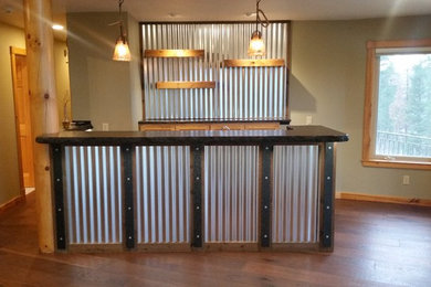 Example of a mid-sized classic galley medium tone wood floor and brown floor wet bar design in Other with a drop-in sink, recessed-panel cabinets, light wood cabinets, granite countertops, black backsplash and stone slab backsplash