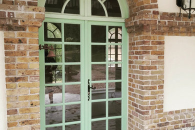 Idée de décoration pour une porte d'entrée tradition avec une porte double et une porte verte.