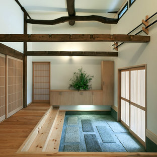 Неиссякаемый источник вдохновения для домашнего уюта: узкая прихожая в восточном стиле с бежевыми стенами, темным паркетным полом, раздвижной входной дверью и коричневым полом