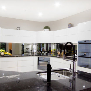 Large modern kitchen pantry appliance - Kitchen pantry - large modern l-shaped porcelain floor and white floor kitchen pantry idea in Sunshine Coast with an undermount sink, granite countertops, mirror backsplash, black appliances and black countertops