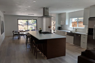 Example of a huge minimalist galley gray floor open concept kitchen design in San Diego with a farmhouse sink, flat-panel cabinets, white cabinets, quartz countertops, white backsplash, stainless steel appliances, an island and white countertops