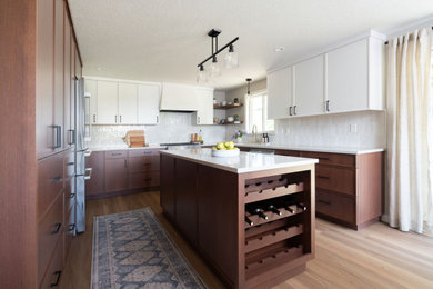 Enclosed kitchen - mid-sized transitional u-shaped light wood floor and brown floor enclosed kitchen idea in Portland with an undermount sink, shaker cabinets, dark wood cabinets, quartz countertops, white backsplash, porcelain backsplash, stainless steel appliances, an island and white countertops