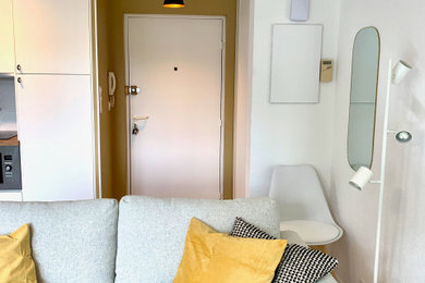 Modelo de entrada actual pequeña con paredes amarillas, suelo de madera clara, puerta simple, puerta blanca y suelo beige