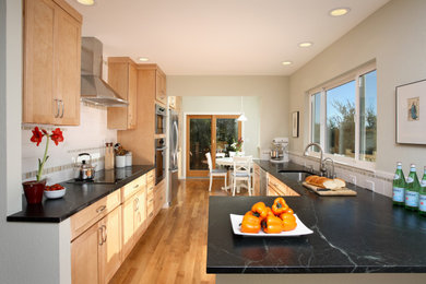 Transitional u-shaped medium tone wood floor and brown floor eat-in kitchen photo in San Francisco with an undermount sink, shaker cabinets, medium tone wood cabinets, quartz countertops, multicolored backsplash, stainless steel appliances, a peninsula and black countertops