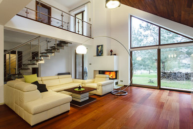 Imagen de salón para visitas abierto escandinavo grande con paredes blancas, suelo de madera en tonos medios y chimenea de doble cara