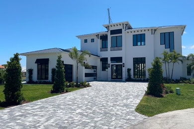 Large tropical two-story stucco house exterior idea in Orlando with a hip roof and a metal roof