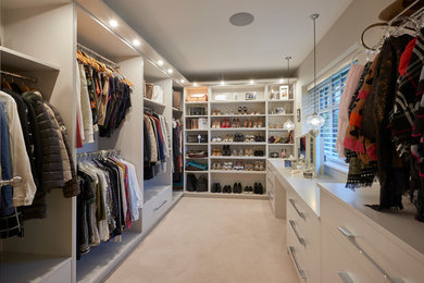 Inspiration for a medium sized contemporary dressing room in Other with carpet, flat-panel cabinets, white cabinets and beige floors.