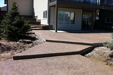 Patio - large backyard concrete paver patio idea in Calgary with a roof extension