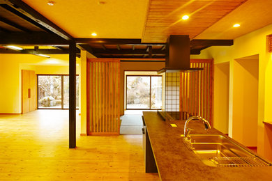 Foto på ett stort funkis svart linjärt kök med öppen planlösning, med en undermonterad diskho, luckor med profilerade fronter, bruna skåp, bänkskiva i koppar, vitt stänkskydd, stänkskydd i keramik, målat trägolv och en halv köksö