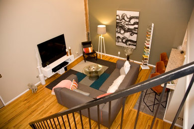 Photo of a mid-sized modern loft-style living room in Denver with multi-coloured walls, light hardwood floors, no fireplace and a freestanding tv.