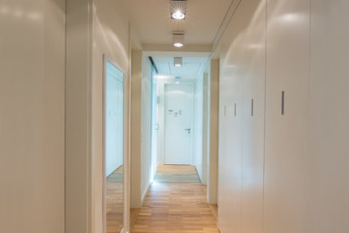 This is an example of a mid-sized contemporary hallway in Cologne with white walls and medium hardwood floors.