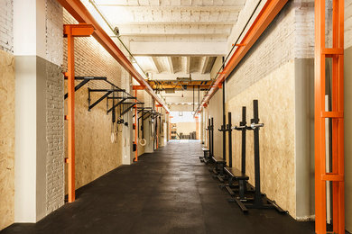 Imagen de sala de pesas grande con paredes marrones y suelo negro