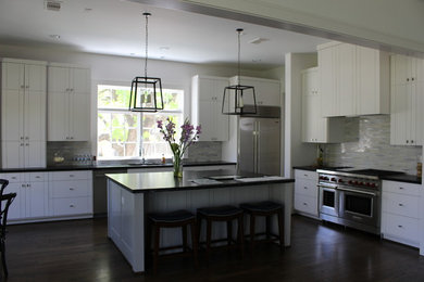 Large elegant single-wall dark wood floor and brown floor kitchen photo in Houston with a double-bowl sink, flat-panel cabinets, white cabinets, matchstick tile backsplash, stainless steel appliances and an island