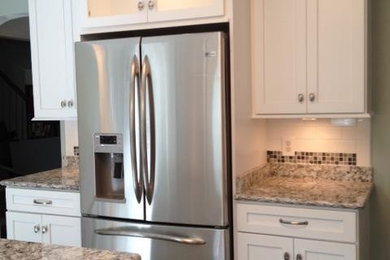 Example of a mid-sized transitional u-shaped eat-in kitchen design in Other with an undermount sink, shaker cabinets, white cabinets, quartz countertops, white backsplash, porcelain backsplash, stainless steel appliances and an island
