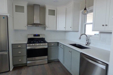 Example of a mid-sized transitional l-shaped medium tone wood floor and brown floor open concept kitchen design in Other with a double-bowl sink, recessed-panel cabinets, gray cabinets, quartz countertops, white backsplash, subway tile backsplash, stainless steel appliances and no island