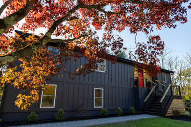 Inspiration for a large black two-story concrete fiberboard and board and batten exterior home remodel in Philadelphia with a shingle roof and a black roof