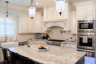 Example of a kitchen design in New Orleans with light wood cabinets, granite countertops, beige backsplash, stainless steel appliances and an island