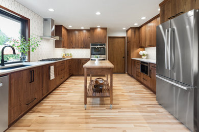 Inspiration for a mid-sized midcentury u-shaped eat-in kitchen in Portland with a double-bowl sink, flat-panel cabinets, dark wood cabinets, quartz benchtops, white splashback, ceramic splashback, stainless steel appliances, light hardwood floors, with island, multi-coloured floor and white benchtop.
