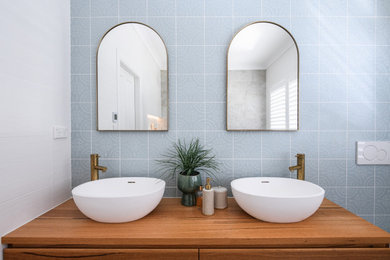 Inredning av ett badrum, med ett fristående badkar, blå kakel, porslinskakel och med dusch som är öppen