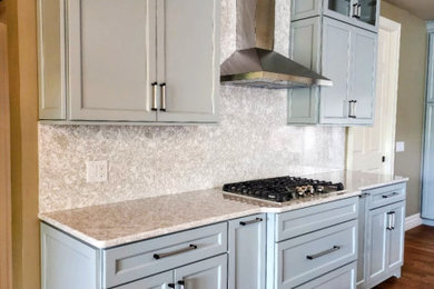 Example of a mid-sized transitional medium tone wood floor and brown floor open concept kitchen design in Other with an undermount sink, shaker cabinets, quartz countertops, white backsplash, quartz backsplash, stainless steel appliances, an island and white countertops