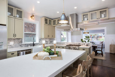 Mid-sized transitional l-shaped eat-in kitchen in San Francisco with a farmhouse sink, shaker cabinets, beige cabinets, quartz benchtops, grey splashback, stone tile splashback, stainless steel appliances, dark hardwood floors, with island and brown floor.