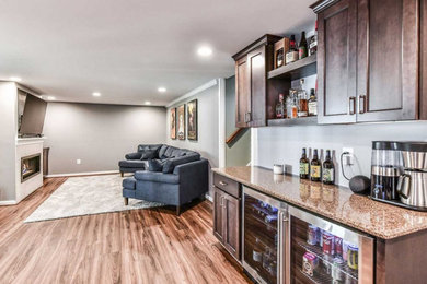 Inspiration for a large transitional walk-out laminate floor and brown floor basement remodel in DC Metro with a bar, gray walls, a ribbon fireplace and a tile fireplace