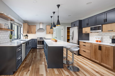 Inspiration for a large transitional u-shaped medium tone wood floor and brown floor enclosed kitchen remodel in Detroit with medium tone wood cabinets, white backsplash, an island, white countertops, an undermount sink, shaker cabinets, quartz countertops, subway tile backsplash and stainless steel appliances