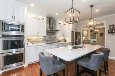 Mid-sized transitional single-wall medium tone wood floor and brown floor open concept kitchen photo in Atlanta with an undermount sink, shaker cabinets, white cabinets, quartz countertops, gray backsplash, glass tile backsplash, stainless steel appliances, an island and white countertops