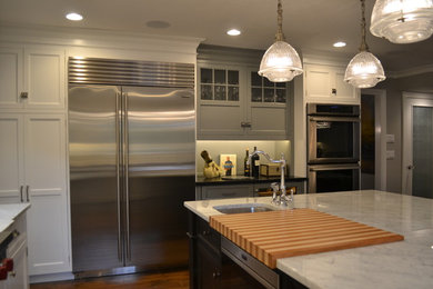 Mid-sized transitional u-shaped dark wood floor eat-in kitchen photo in New York with a farmhouse sink, shaker cabinets, white cabinets, marble countertops, white backsplash, subway tile backsplash, stainless steel appliances and an island