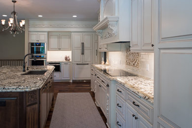 Elegant dark wood floor eat-in kitchen photo in Minneapolis with an undermount sink, raised-panel cabinets, white cabinets, granite countertops, yellow backsplash, cement tile backsplash, paneled appliances, an island and beige countertops