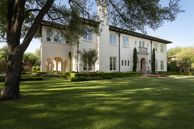 This is an example of a large mediterranean two-storey stucco white exterior in Dallas with a hip roof.