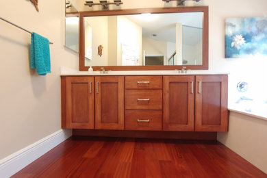 Diseño de cuarto de baño principal, doble y a medida con armarios estilo shaker, puertas de armario de madera oscura, suelo de madera en tonos medios, encimera de cuarzo compacto y encimeras blancas