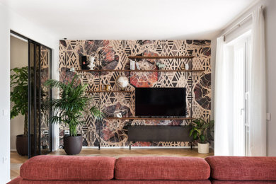 Ejemplo de biblioteca en casa abierta grande con suelo de madera clara, televisor colgado en la pared y papel pintado