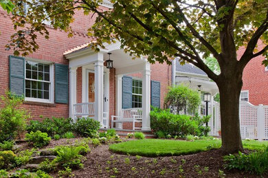 Large elegant red two-story brick house exterior photo in DC Metro with a hip roof and a shingle roof