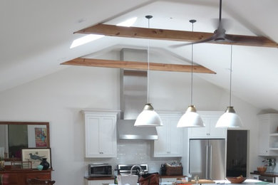 Example of a mid-sized eclectic l-shaped medium tone wood floor open concept kitchen design in Atlanta with shaker cabinets, white cabinets, quartz countertops, white backsplash, subway tile backsplash, stainless steel appliances, an island and white countertops