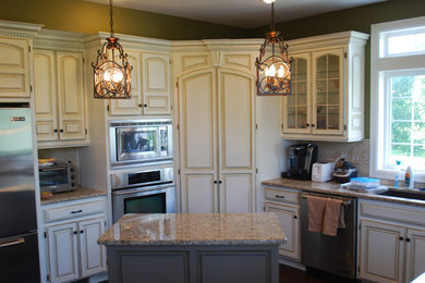 Enclosed kitchen - mid-sized traditional galley dark wood floor enclosed kitchen idea in Kansas City with an undermount sink, raised-panel cabinets, white cabinets, granite countertops, beige backsplash, stone tile backsplash, stainless steel appliances and an island