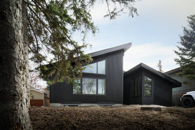 Modelo de fachada de casa negra y negra minimalista de tamaño medio de una planta con revestimientos combinados, tejado de un solo tendido y tejado de teja de madera