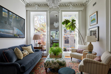 Inspiration for a mid-sized traditional formal enclosed living room in New York with beige walls, medium hardwood floors, a wall-mounted tv and brown floor.