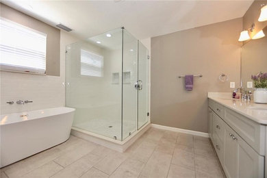 Photo of a large classic ensuite bathroom in Orlando with shaker cabinets, white cabinets, a freestanding bath, a corner shower, white tiles, metro tiles, beige walls, porcelain flooring, a submerged sink, marble worktops, beige floors, a hinged door and white worktops.
